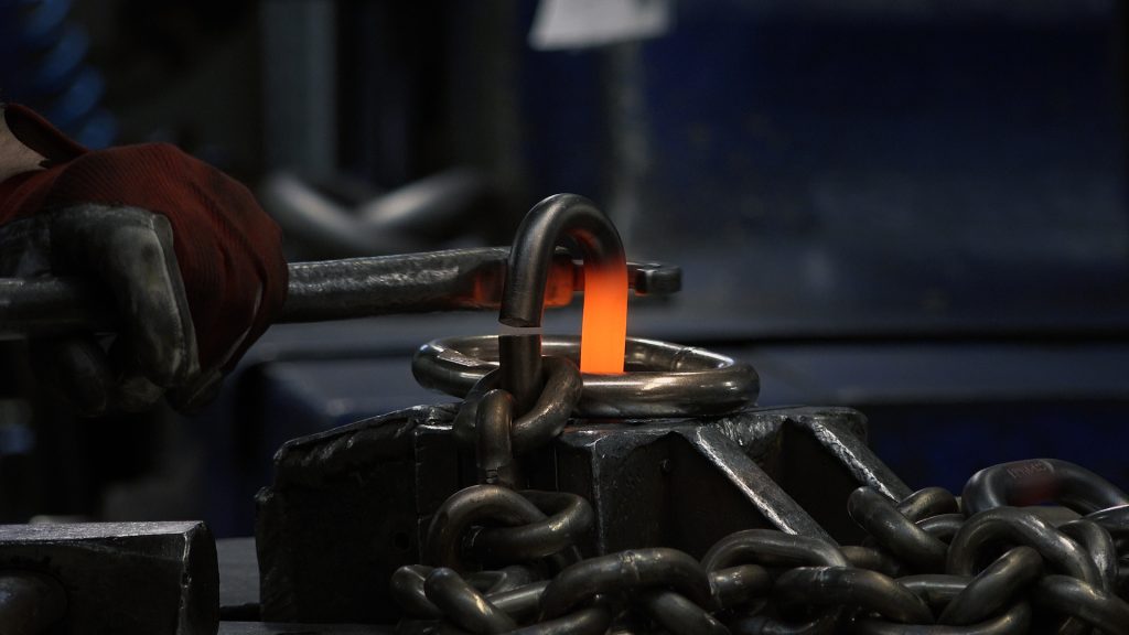 A pewag chain link under construction and glowing molten orange