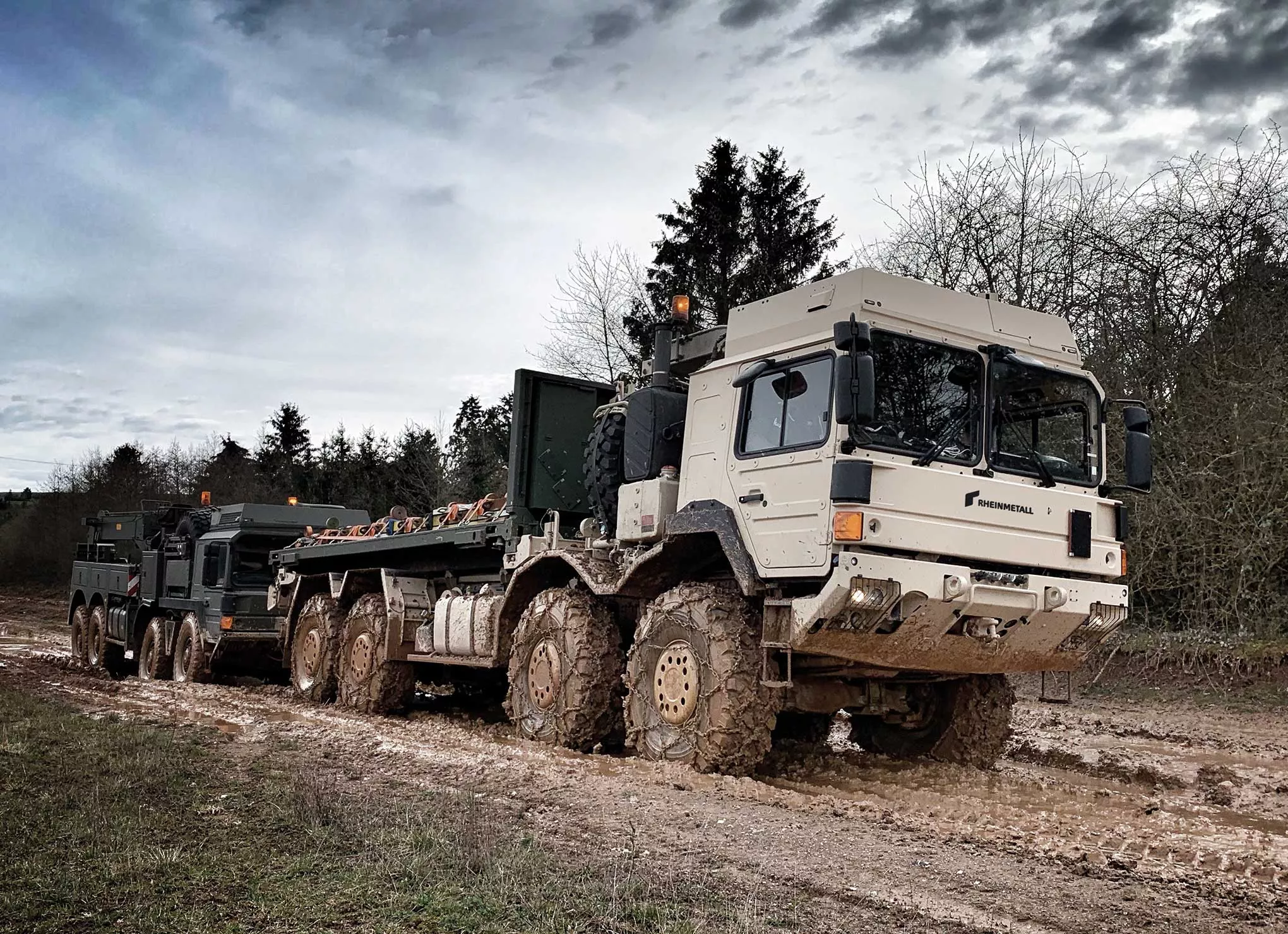 Military transport truck driving through muddy off-road terrain