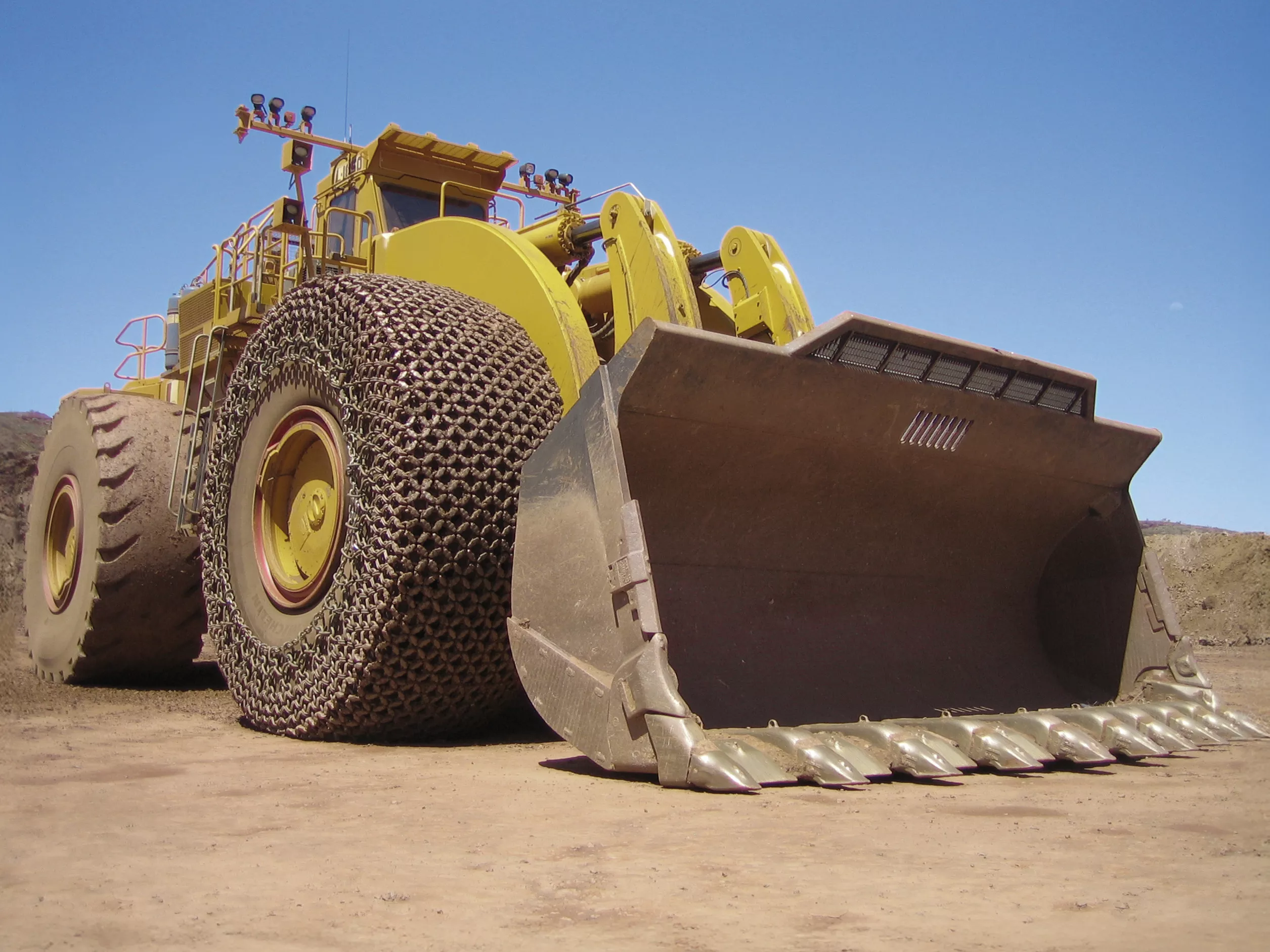 A large earth mover in a quarry setting with tyre protection chains from pewag fitted to the front tyres.