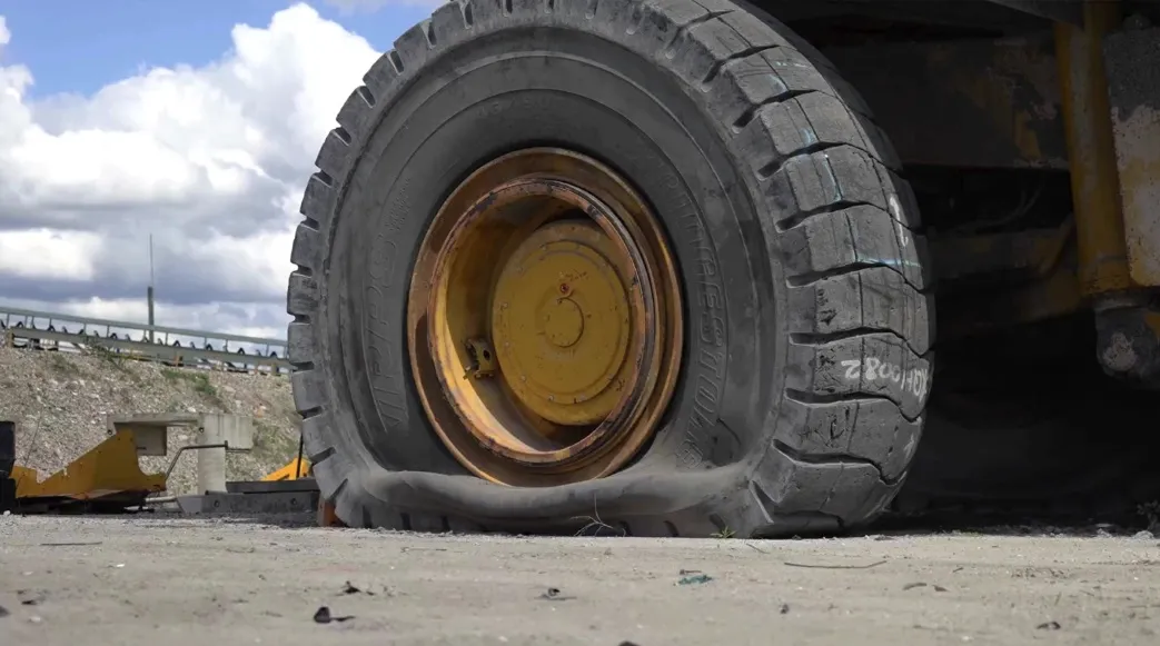 A giant earth mover vehicle has suffered a tire blowout in a quarry setting