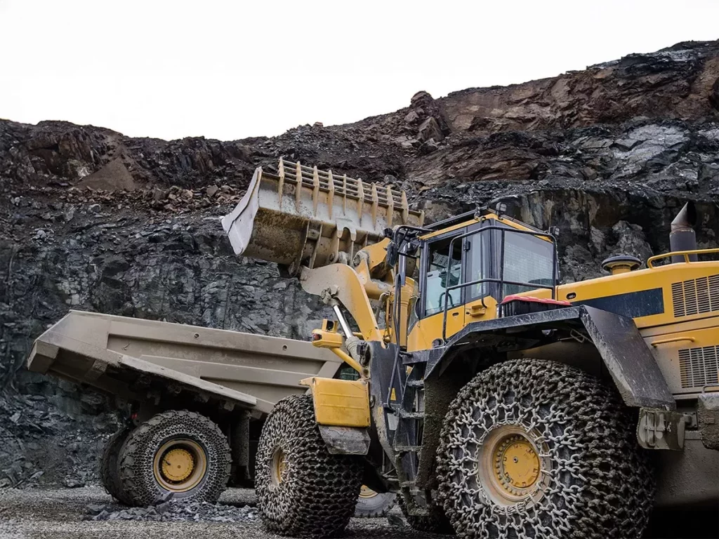 An earth mover loads a dumper truck with quarry material