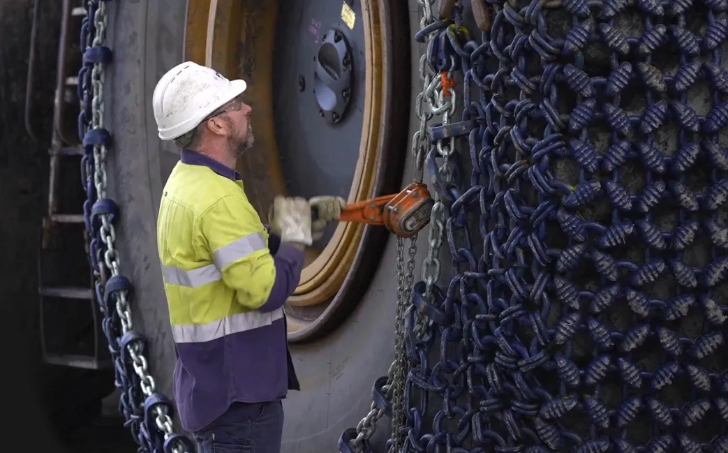 An operative installing tire protection chains to a large earth moving vehicle